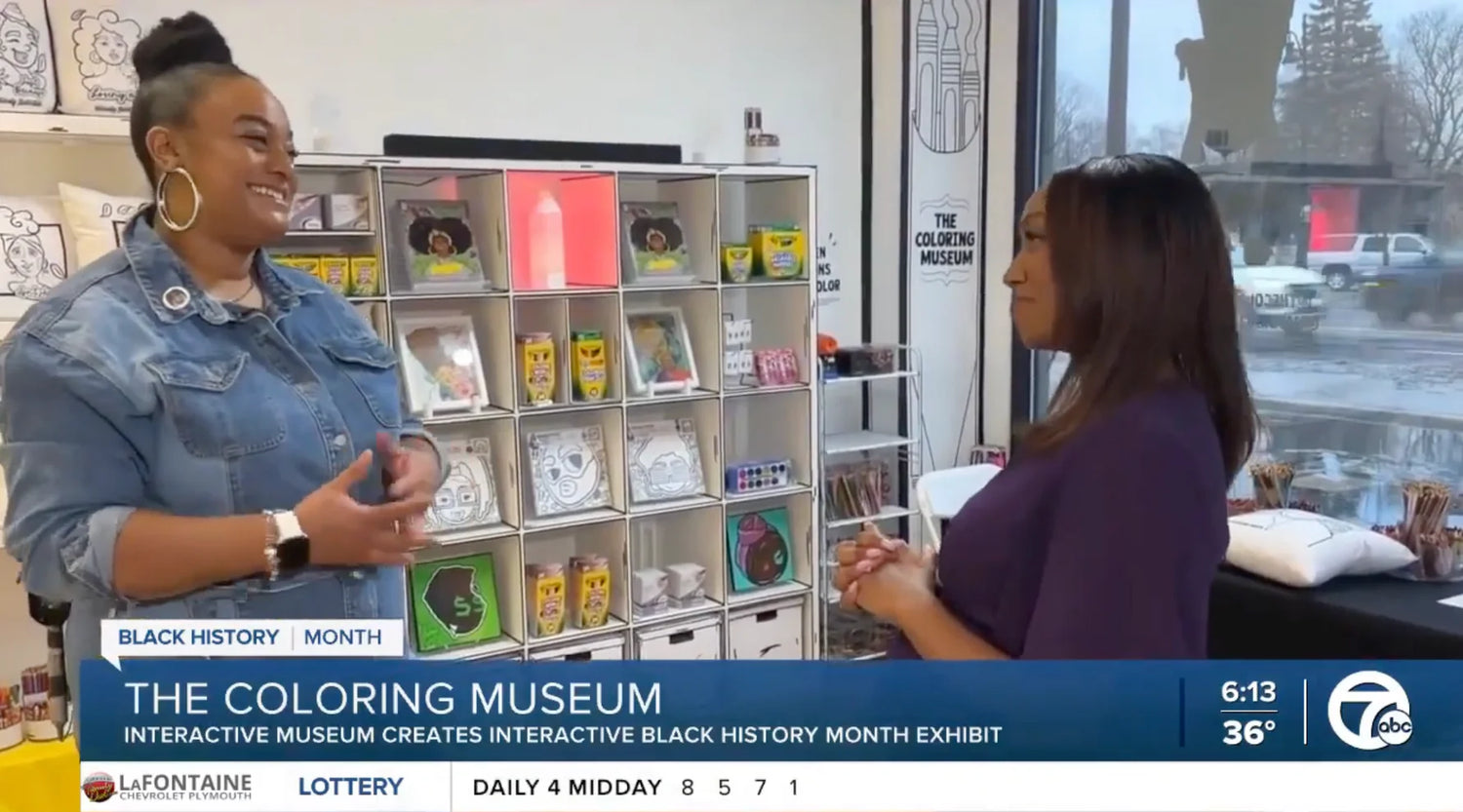 Two women are having a conversation in The Coloring Museum, surrounded by colorful displays and products. A news banner at the bottom mentions Black History Month and an interactive exhibit.