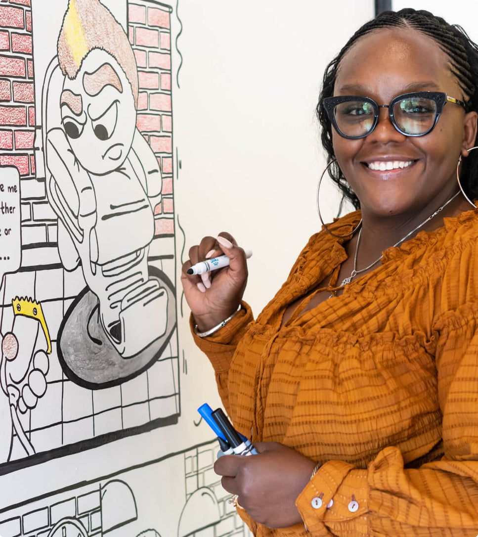 A woman coloring an illustration on the wall at The Coloring Museum