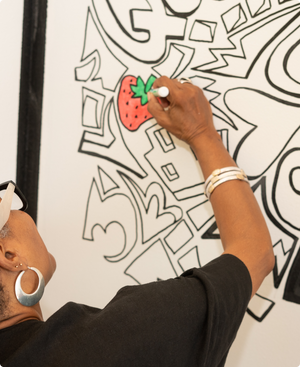 Woman coloring in strawberry on the wall at The Coloring Museum