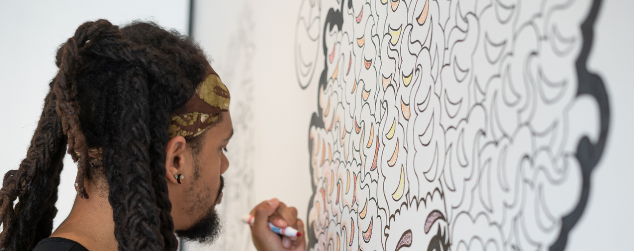 Man coloring in an illustration on the wall at The Coloring Museum